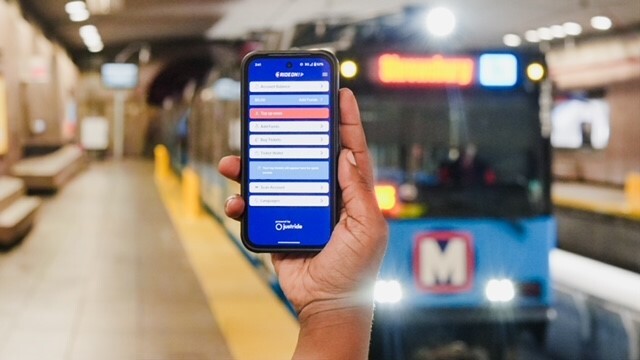 A phone with the RideOn! app with a MetroLink train in the background